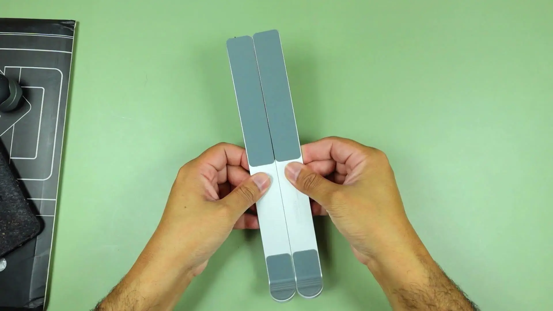 The UGREEN aluminum laptop stand's two solid metal legs held up during unboxing, showing the full-metal build