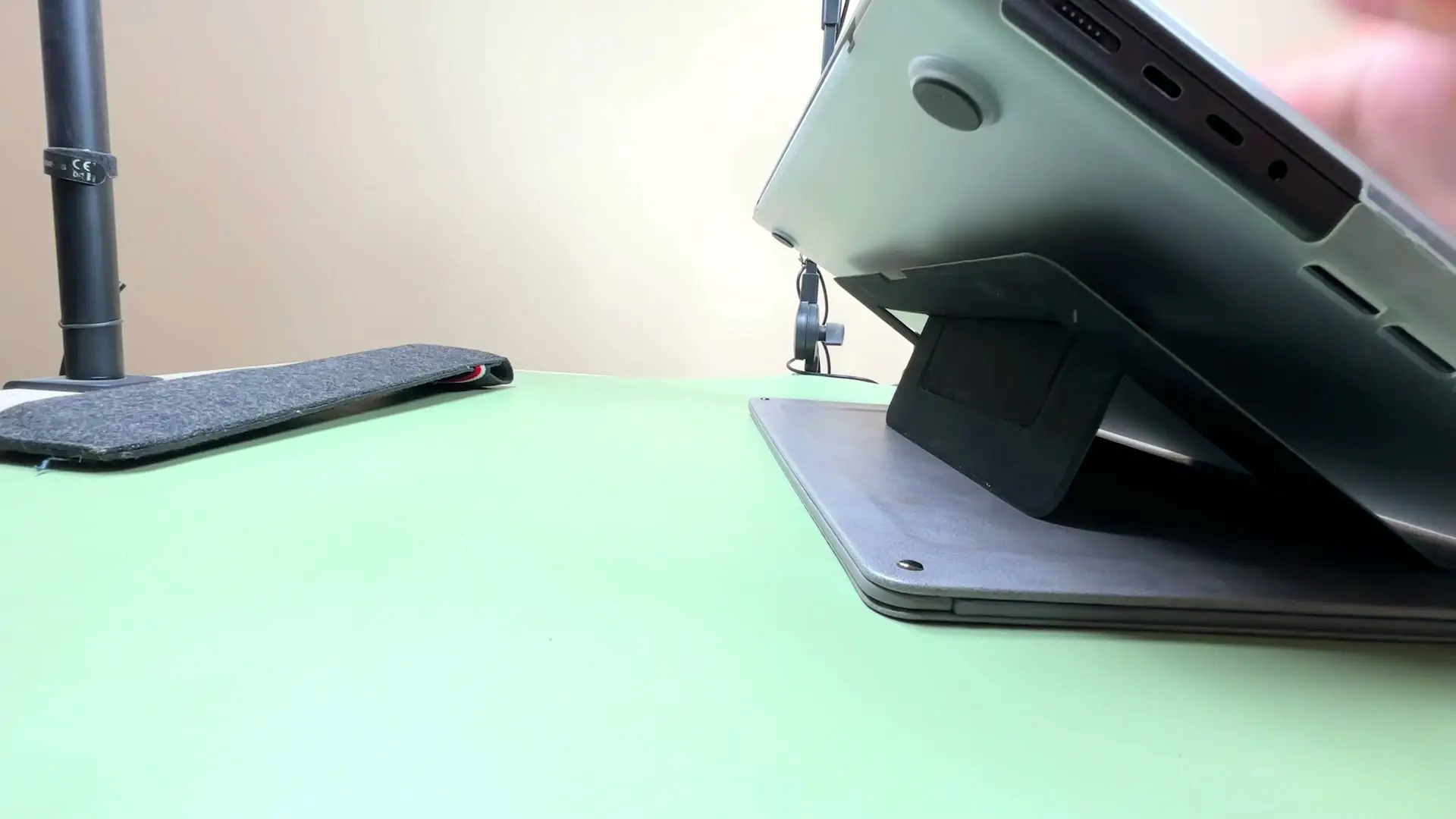 A 16-inch MacBook Pro resting on a folding laptop stand during the real-world load test, the stand's structure visibly supporting the laptop's weight