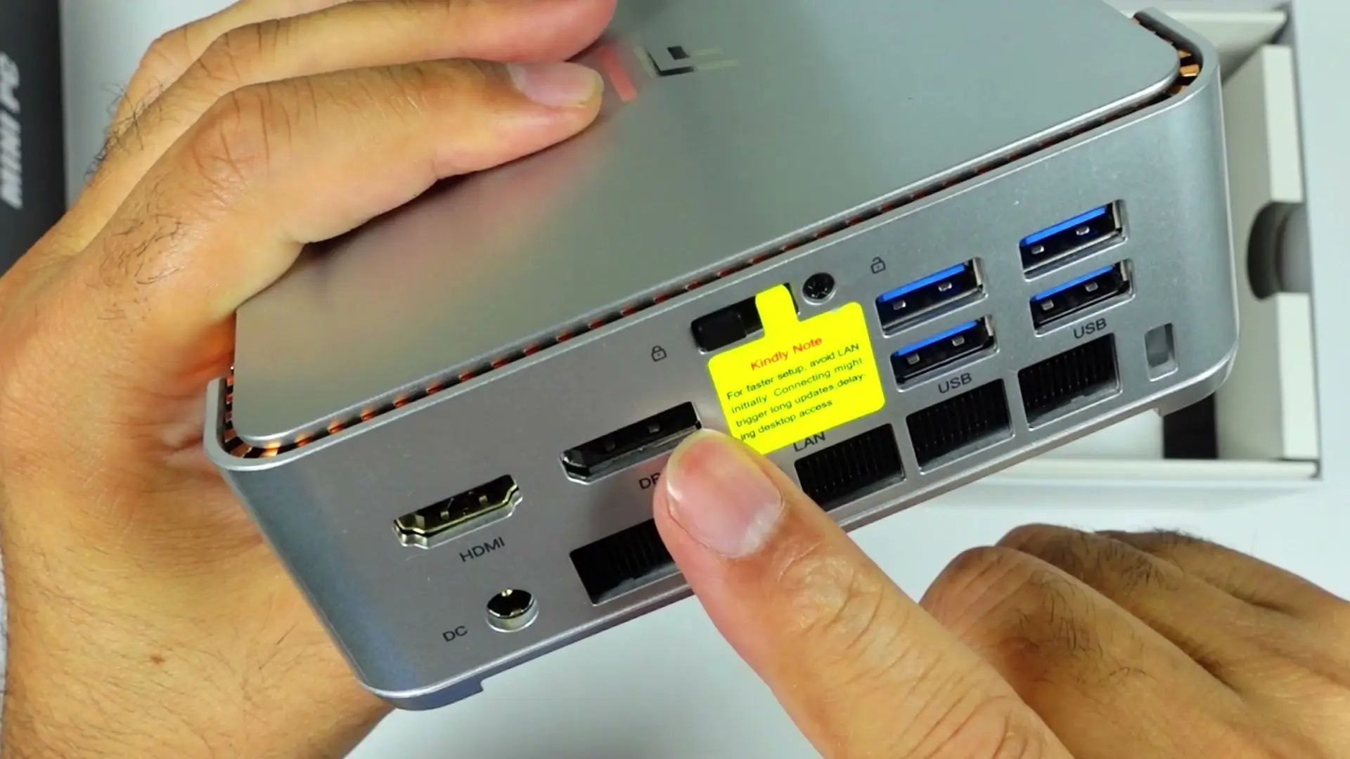 Back of the KAMRUI Hyper H2 showing DC in, HDMI, LAN and four blue USB-A ports, with a yellow sticker over one port