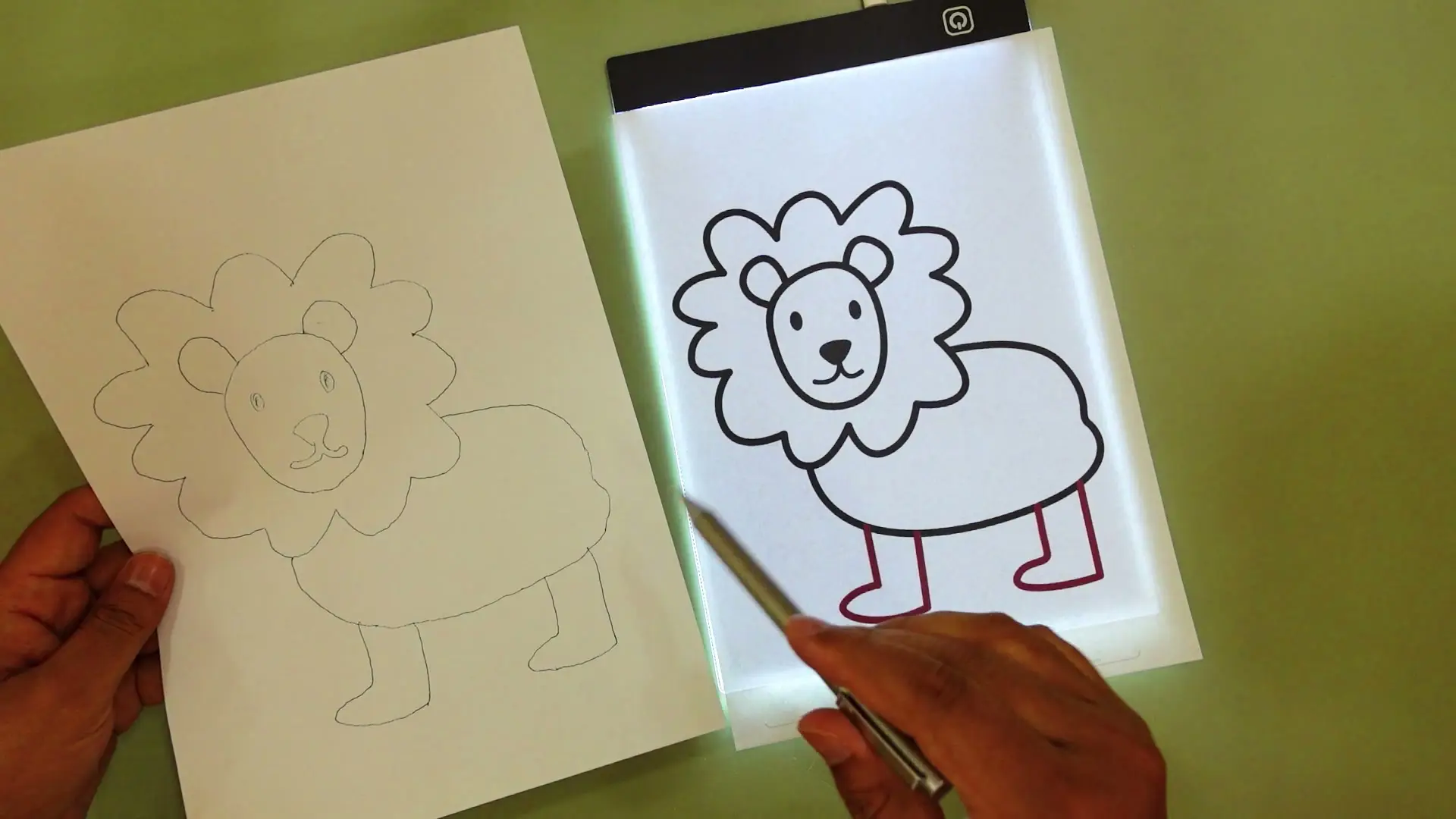 The hand-traced lion drawing held up beside the original printed outline sheet, showing how closely the traced result matches the source
