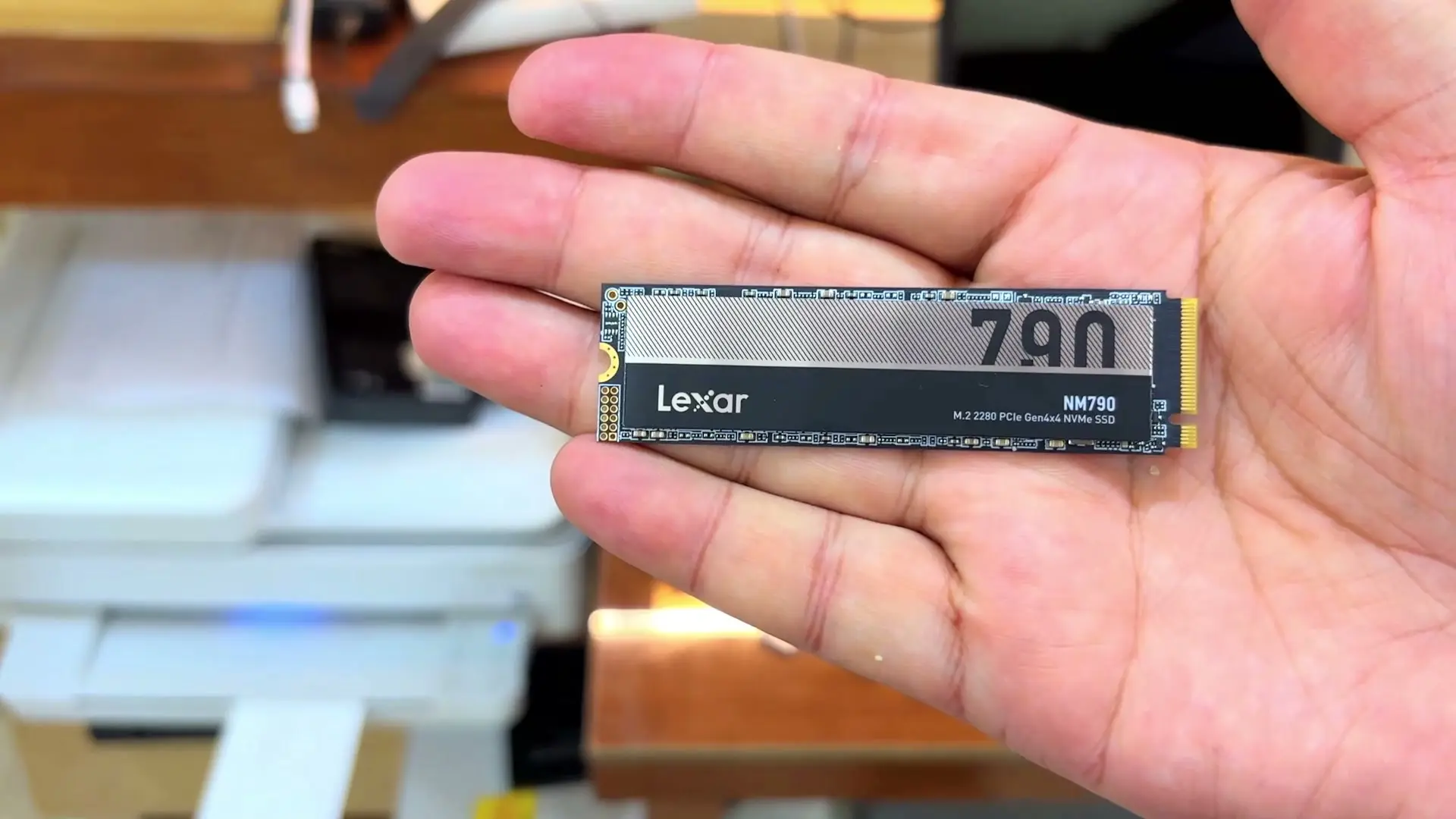 A Lexar NM790 M.2 2280 NVMe SSD held flat in an open hand, its label showing the Lexar logo, a large 790 and NM790