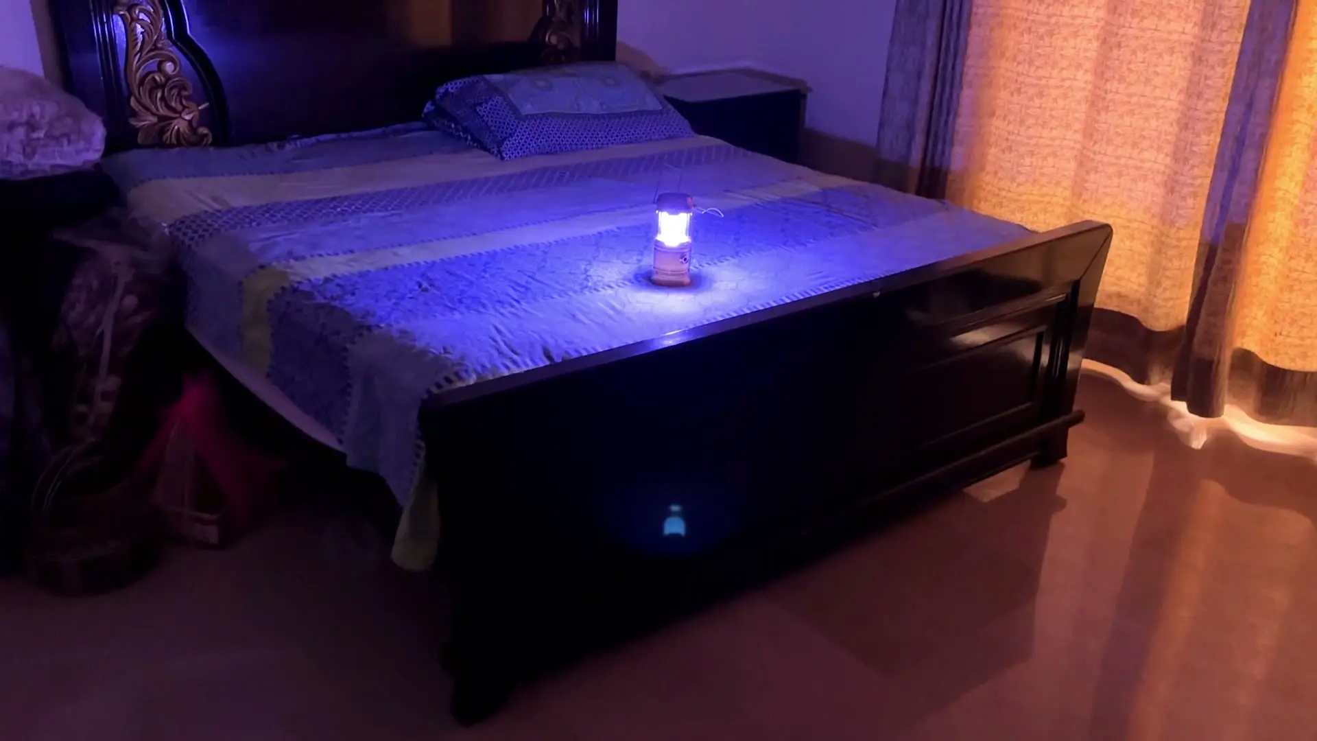 The lit lantern in a dim bedroom with the main lights off, showing its light output is limited to a localized glow rather than filling the room