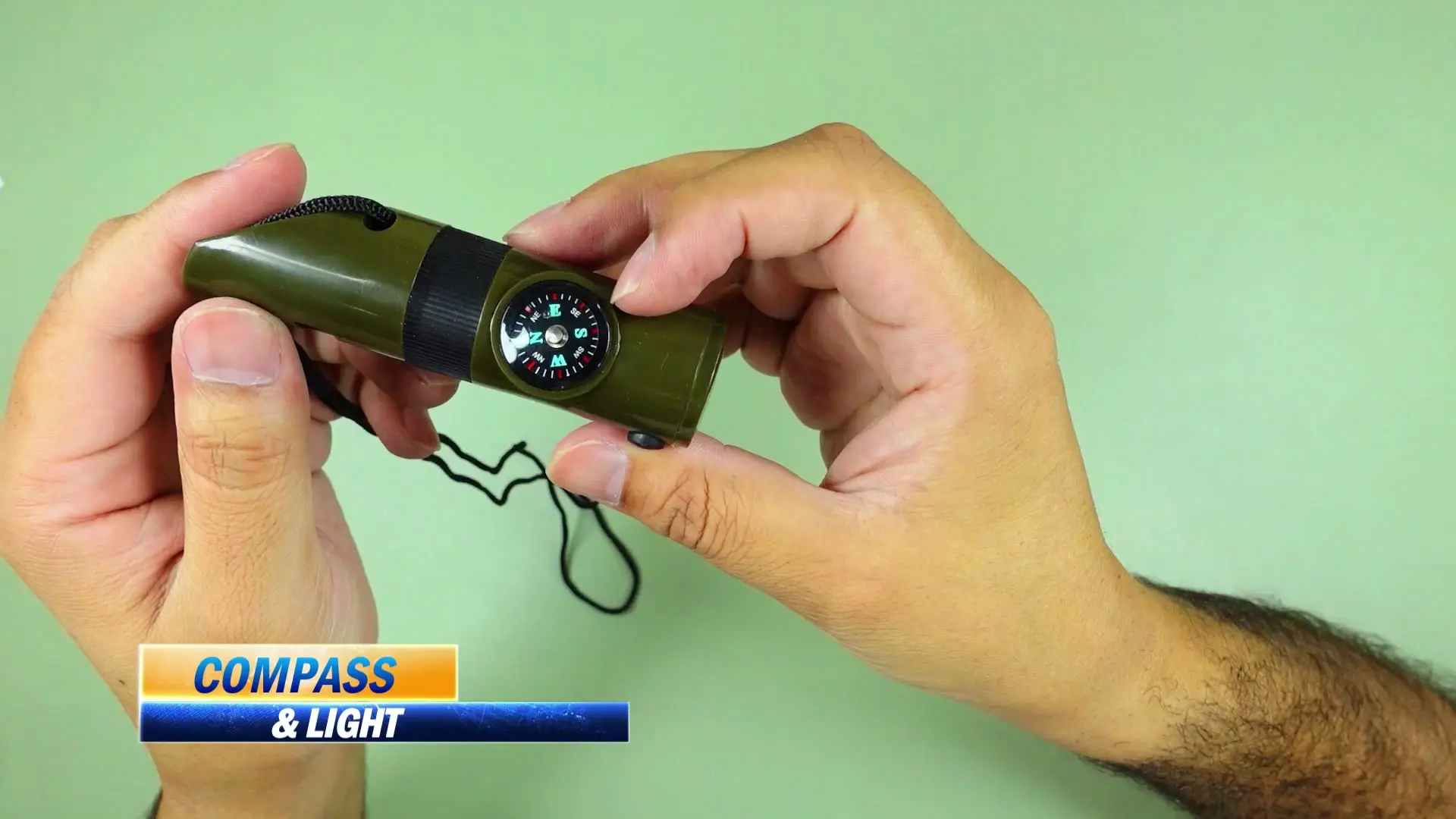 The 7-in-1 survival whistle held in hand with its built-in compass dial visible