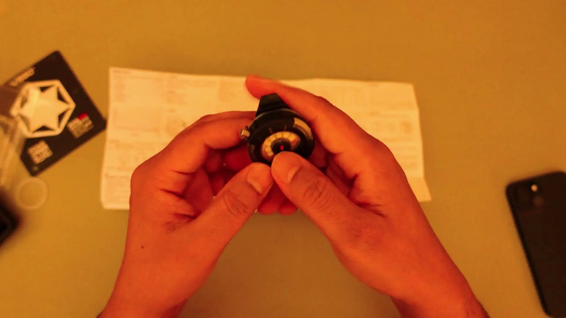 Hands lit red while testing the EDC flashlight's camping light mode in a dimmed room