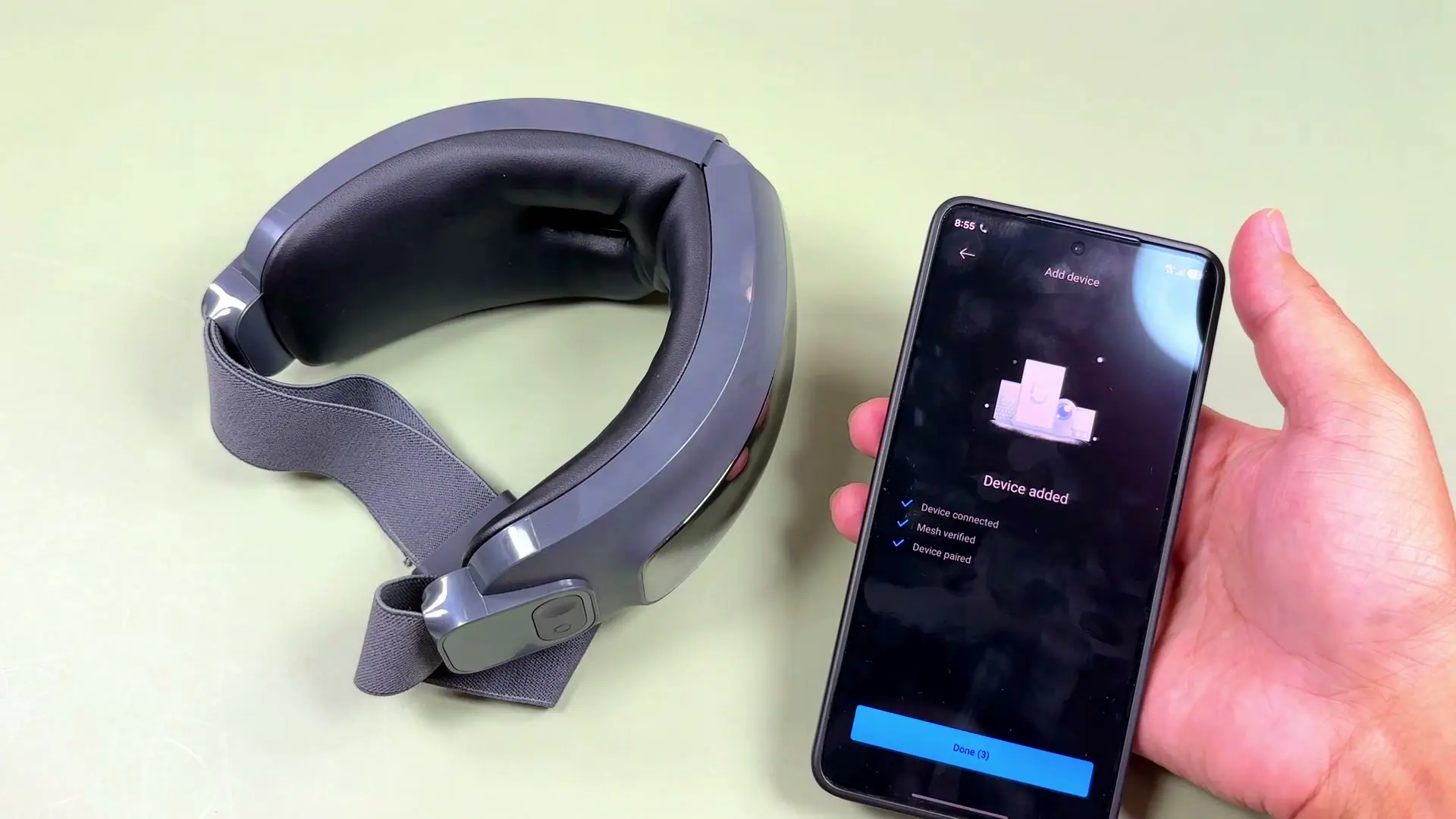 Phone showing Mi Home device added success screen next to the folded eye massager on a green mat