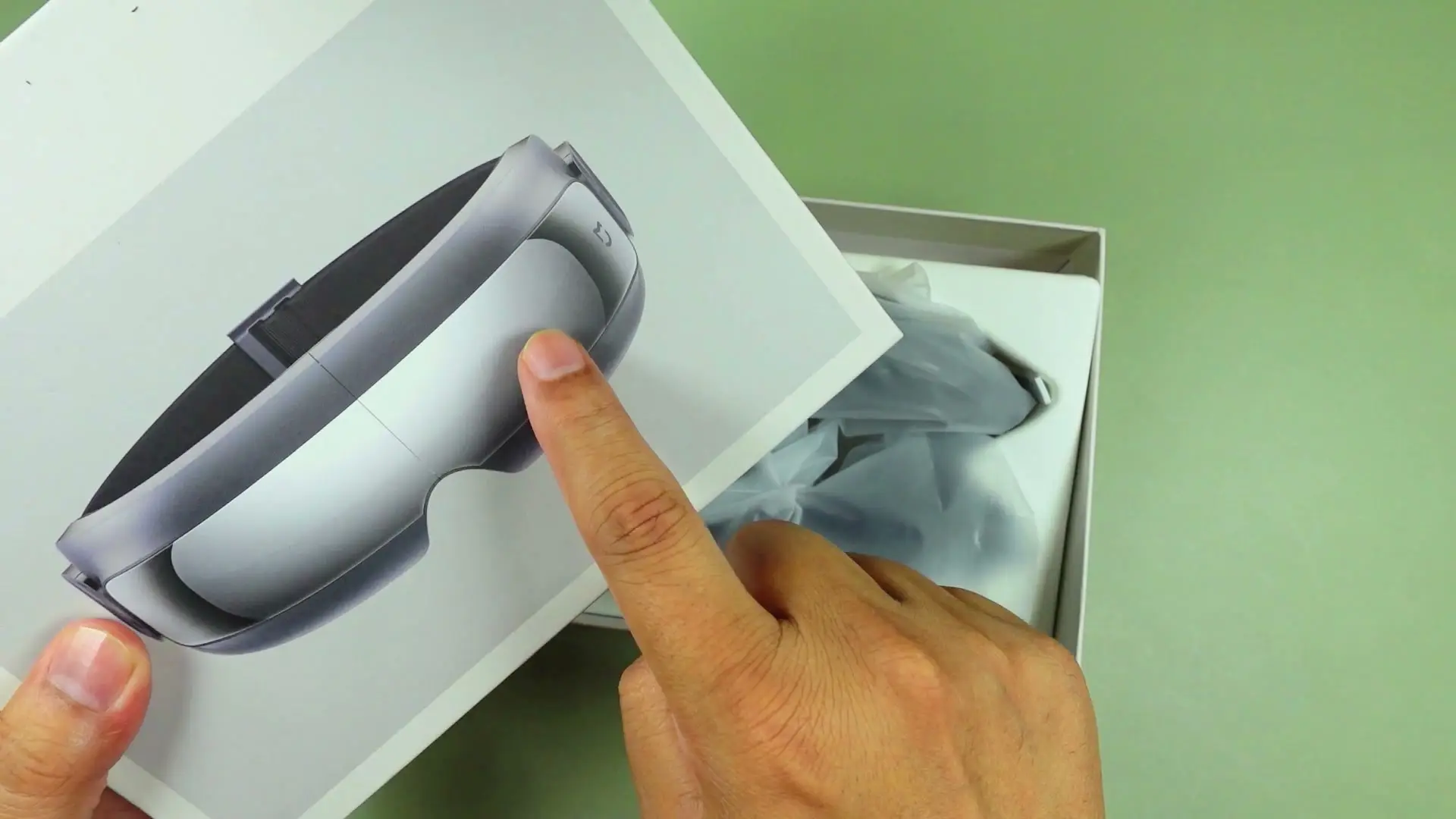 Unboxed Xiaomi Mijia Smart Eye Massager with gray carry pouch and documentation on a green mat