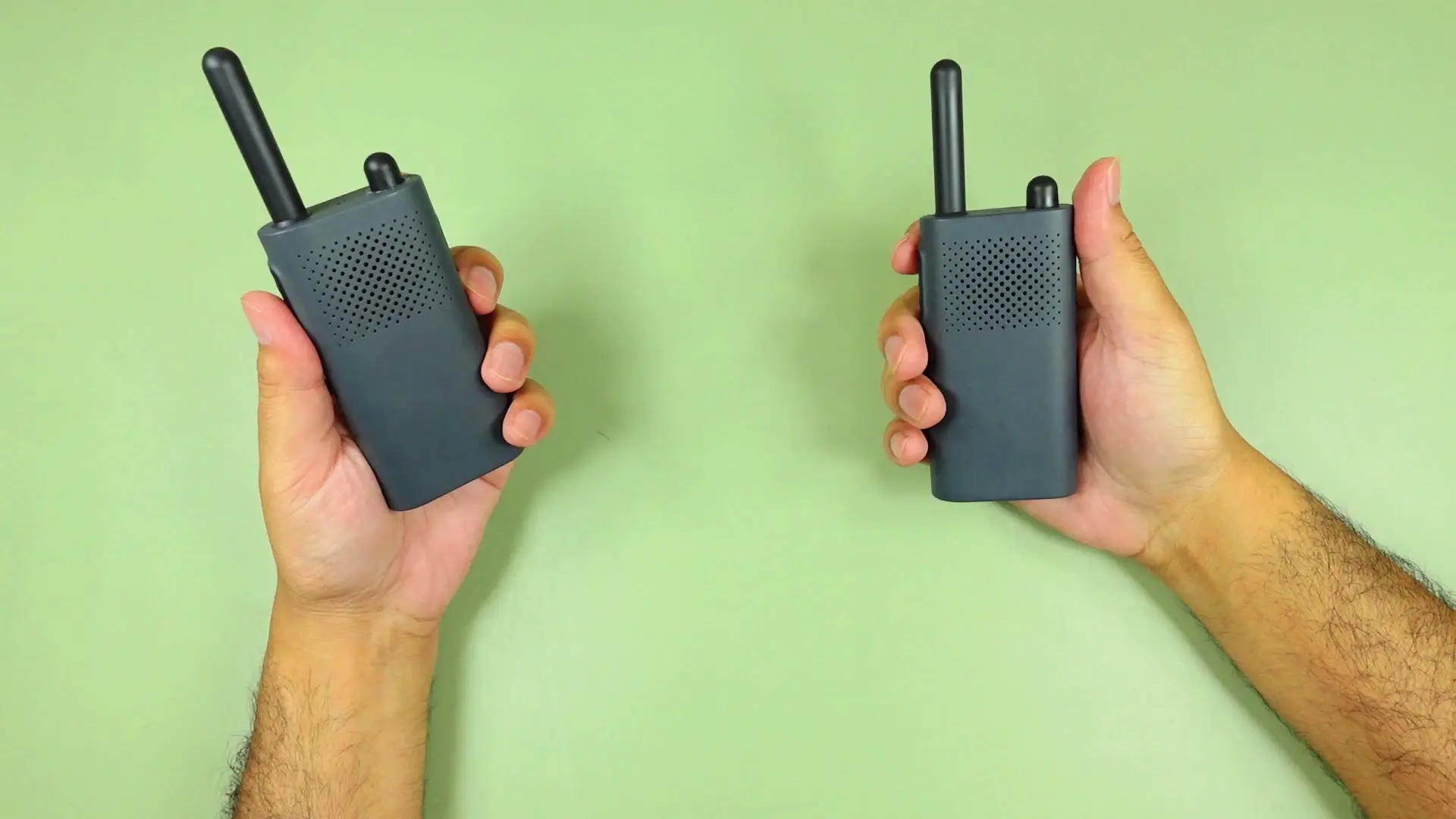 Two hands holding Xiaomi Walkie Talkie 3 Lite units with antennas up and green and orange status LEDs lit